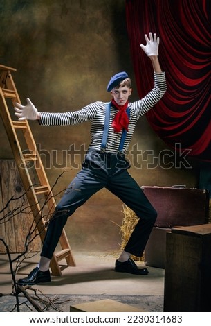 Retro circus show. Vintage portrait of male mime artist expressing sadness and loneliness over dark retro circus backstage background. Concept of emotions, art, fashion, style Royalty-Free Stock Photo #2230314683