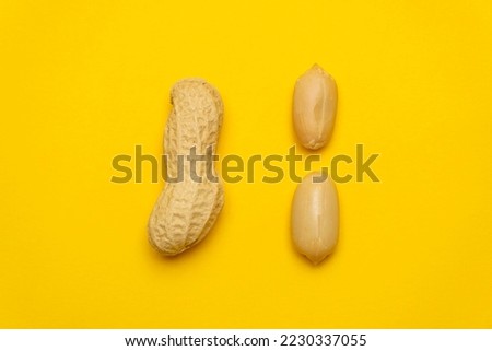 Whole peanut in the shell and peeled on a yellow background. Protein and healthy dried fruit. Cool minimal flat lay, copy space 