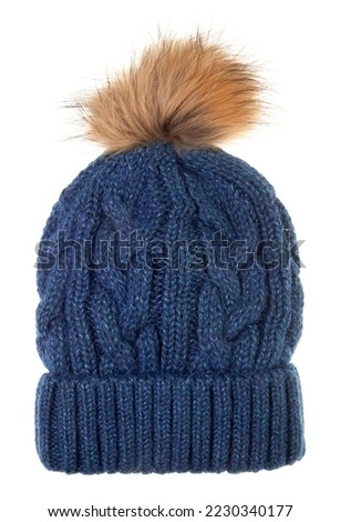 Blue woolly winter bobble hat decorated with cable knitting ornament isolated on white background. Handmade woolly cap with fake fur pompom on top Royalty-Free Stock Photo #2230340177
