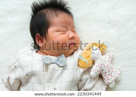 A picture taken with a sleeping 1-month-old 0-year-old newborn and a girl's stuffed animal on the left and a white background