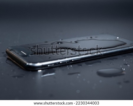 Close-up of an old telephone in water on a black background. Wet smartphone. Royalty-Free Stock Photo #2230344003