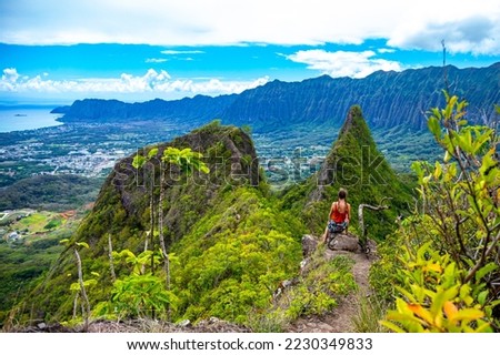 hiker girl stands at the top of olomana ridge trail admiring the panorama of oahu and hawaii mountains; famous three peaks on oahu, dangerous hiking on hawaii mountains, hawaii holidays Royalty-Free Stock Photo #2230349833