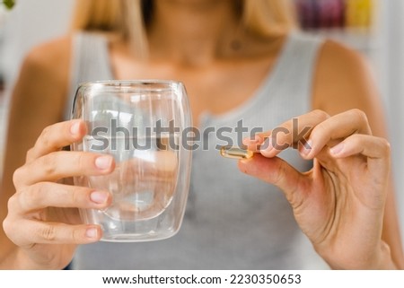 Collagen supplement capsules with cup of water in hands. Collagen pills to support skin health. BADS biologically active dietary supplements for healthcare Royalty-Free Stock Photo #2230350653