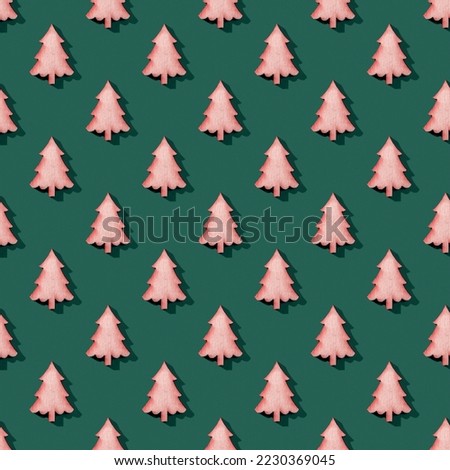 Seamless pattern of wooden fir tree silhouettes over green background. Christmas Eve and New Year macro texture. Winter holidays design element in reddish green colors. Hard light shot. Top view.