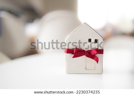 Merry Christmas and happy new year horizontal banner with small toy model house wrapped in red satin ribbon on a white background. High quality photo