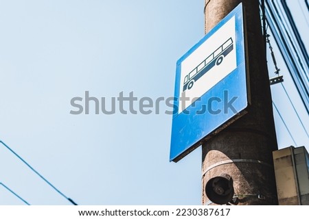 Close-up to a bus stop sign shot from below in perspective while mounted on a concrete pole