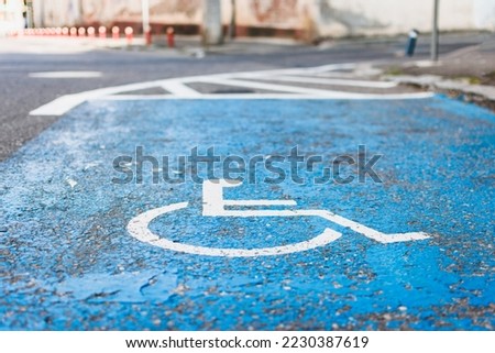 Parking lot for disabled people marked with graphic on asphalt in blue and white colors