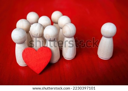 group of wooden figurines holding a red heart and one figure stands by itself Royalty-Free Stock Photo #2230397101