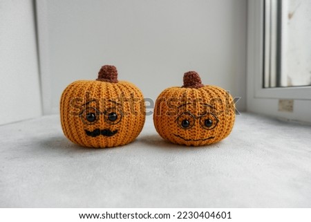 Knitted pumpkins of different colors, crocheted on a light background. Handmade for autumn decor. Halloween and Thanksgiving. Knitting toys, hobby.