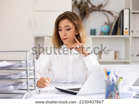 Portrait of young attractive woman secretary working at her desktop, using laptop.