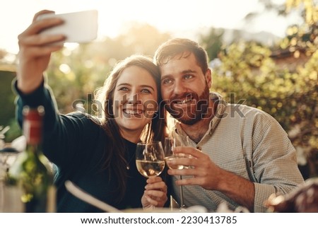Wine, phone and couple take a selfie with a toast to a happy marriage and share romantic content on social media. Woman smiles taking pictures on a date with a lovely partner drinking champagne