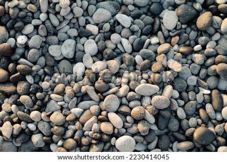 Multi-colored volcanic sea stones of different shapes backdrop from Kamari Beach, Greece