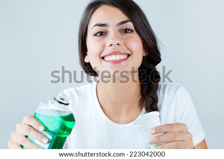 Portrait of beautiful girl using mouthwash. Isolated on white. Royalty-Free Stock Photo #223042000