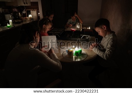 Family spending time together during an energy crisis in Europe causing blackouts. Kids drawing in blackout. Royalty-Free Stock Photo #2230422231