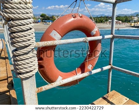 Round non-sinking red lifebuoy for safety to save the lives of drowning people tourists against the background of the sea in a warm eastern tropical country southern paradise resort.