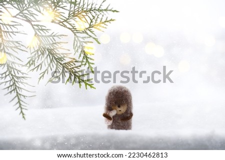 Cute little hedgehog on snowy winter background, christmas tree branches, snowflakes, snow, blurred background. Hedgehog in fog. New Year or Christmas holidays background, copy space