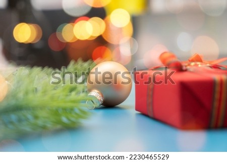 Christmas spruce with ball, gift and blurred shiny lights. Christmas or New Year Holiday atmosphere.