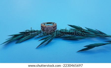 Ring, dry leaves, on a blue background.
