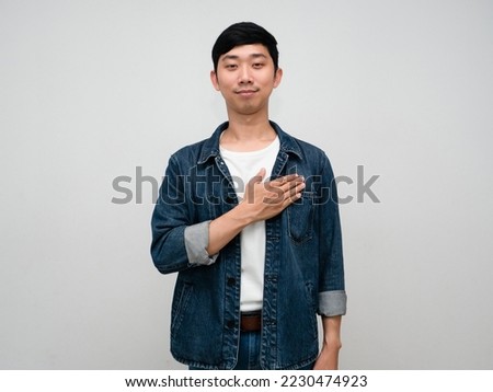 Positive asian man jeans shirt gesture hold his chest wish to peaceful isolated Royalty-Free Stock Photo #2230474923