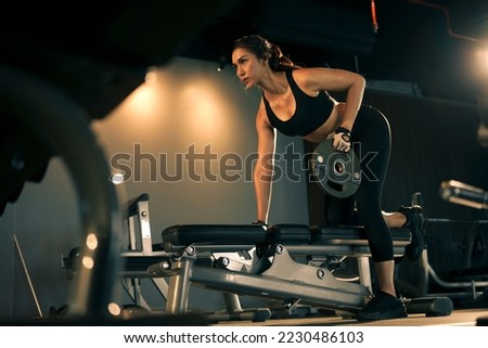 Sporty woman exercising with weight plate in the gym. Royalty-Free Stock Photo #2230486103