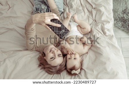Young mother with her little daughter makes selfie while lying on the bed. Happy family concept
