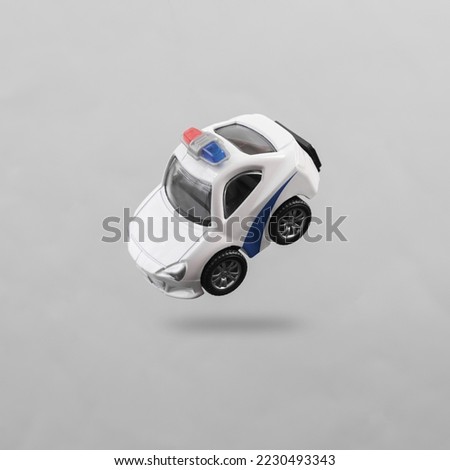 Toy police car levitating on gray background with shadow