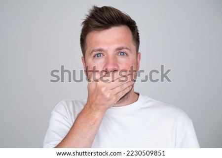 Keeping your secret. man covering mouth with hand and looking at camera. Royalty-Free Stock Photo #2230509851