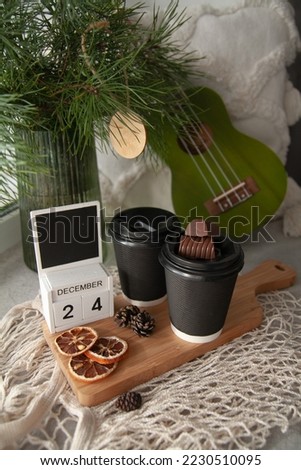 Glasses with hot drinks, chocolate, a Christmas tree and a calendar with the inscription December 24.  Christmas Eve