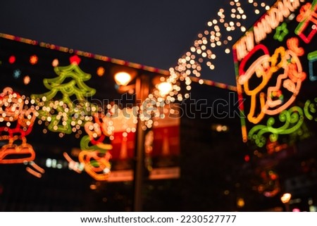 Bokeh effect of Christmas Lighting decoration on the street. Green blurred Christmas tree and Santa Claus