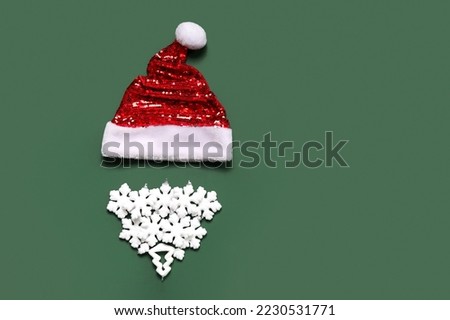 Santa hat and beard made of Christmas decor on green background