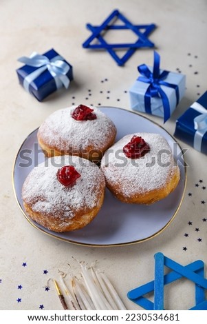 Plate of tasty donuts for Hanukkah celebration, gifts and decor on light background