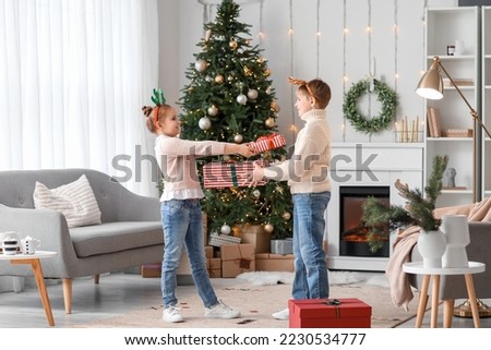 Little children greeting each other with Christmas presents at home