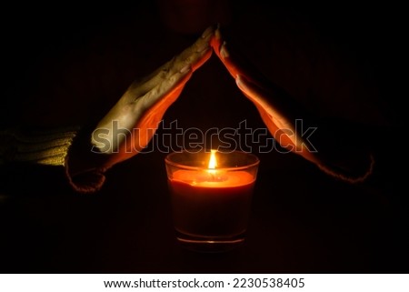 Burning candle in female hands. A black background