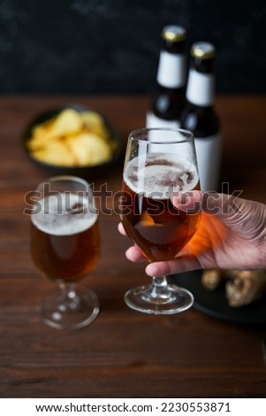 Two glasses with beer, snacks and bottles