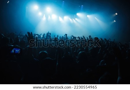 Concert crowd raving to the music. Big group of young people partying on musical festival in night club Royalty-Free Stock Photo #2230554965