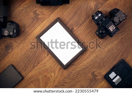 Wooden photo frame on a wooden background. Photography equipment and photo frame. Camera, lens, frame.