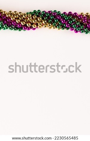 Composition of colourful mardi gras beads with copy space on white background with copy space. Party, celebration and carnival concept.