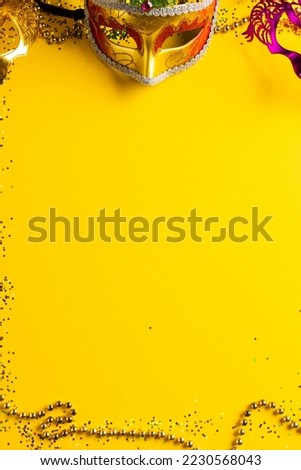 Composition of colourful mardi gras beads and carnival masks on yellow background with copy space. Party, celebration and carnival concept.