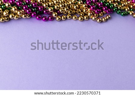 Composition of colourful mardi gras beads on lilac background with copy space. Party, celebration and carnival concept.