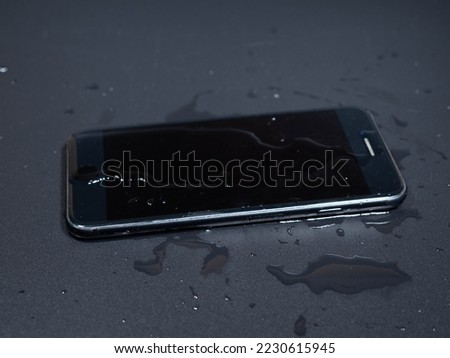 Close-up of an old telephone in water on a black background. Wet smartphone.