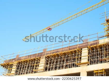 Crane and building construction site against blue sky. Construction of new residential high-rise building