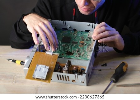 repair of a satellite tuner by a person on a table and a gray background