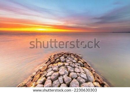 Typical basalt breakwater pier construction at  IJsselmeer near the town of Hindeloopen in the Friesland Province at sunset, Netherlands.