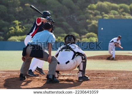Baseball players in action on the stadium, baseball batter waiting to strike the ball. Baseball pitcher following through to pitch to right handed batter
