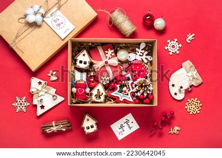 Handmade christmas care package, seasonal gift box with toys, xmas decor on red table Personalized eco friendly basket for family, friends, girl for 24 December, Christmas, New Year day Flat lay Royalty-Free Stock Photo #2230642045