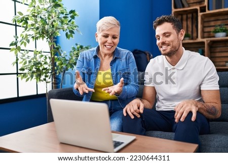 Mother and son having video call sitting on sofa at home