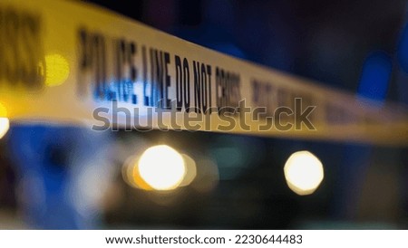 Yellow Tape Showing Text "Police Line Do Not Cross" Restricting a Crime Scene Area At Night. Close Up Aesthetic Shot with Bokeh Effect. Text Blurred. Criminal on the Loose Strikes Again Royalty-Free Stock Photo #2230644483