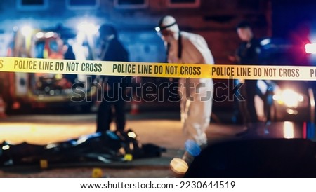 Close Up Shot Focused on Yellow Tape Showing Text "Police Line Do Not Cross". Restricted Area of a Crime Scene. Bokeh Background with Flickering Siren Lights. Forensics Team Working on a Case Royalty-Free Stock Photo #2230644519