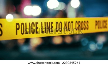 Yellow Tape Showing Text "Police Line Do Not Cross" Restricting a Crime Scene Area At Night. Close Up Aesthetic Shot with Bokeh Effect and Flickering Lights. Criminal on the Loose Strikes Again Royalty-Free Stock Photo #2230645961