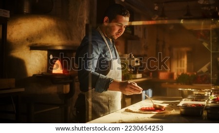 In Restaurant Professional Chef Uses Pizza Peel for Transferring Pizza into Wood Fire Stone Oven. Traditional Italian Cooking Family Recipe. Authentic Pizzeria with Delicious Organic Food Royalty-Free Stock Photo #2230654253